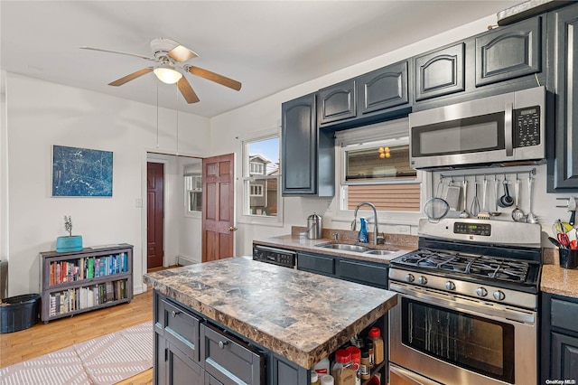 kitchen featuring ceiling fan, sink, light hardwood / wood-style flooring, a kitchen island, and appliances with stainless steel finishes