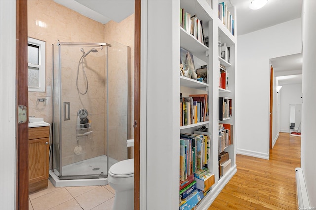 bathroom with vanity, a baseboard heating unit, toilet, an enclosed shower, and wood-type flooring