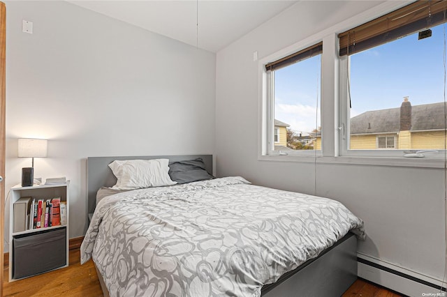 bedroom featuring baseboard heating and hardwood / wood-style floors