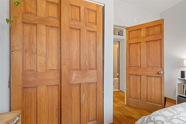 bedroom with connected bathroom and light hardwood / wood-style flooring