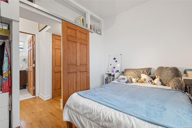 bedroom featuring light wood-type flooring and ensuite bathroom