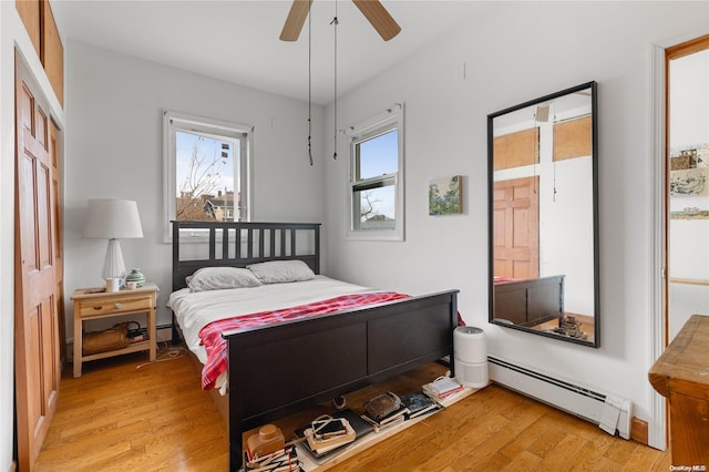 bedroom featuring light hardwood / wood-style flooring, ceiling fan, and a baseboard heating unit