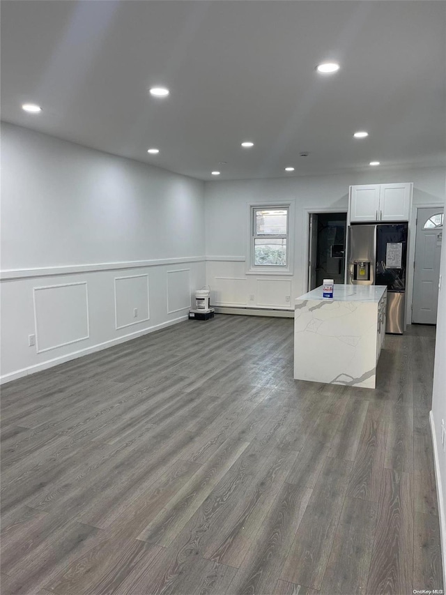 kitchen with a baseboard heating unit, white cabinets, light stone countertops, dark hardwood / wood-style flooring, and stainless steel fridge with ice dispenser