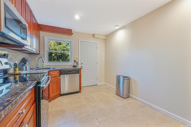 kitchen featuring decorative backsplash, sink, stainless steel appliances, and dark stone counters