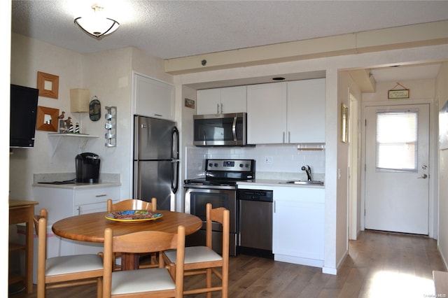 kitchen with decorative backsplash, appliances with stainless steel finishes, dark wood-type flooring, sink, and white cabinetry