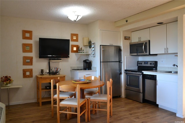 kitchen with white cabinets, sink, a textured ceiling, dark hardwood / wood-style flooring, and stainless steel appliances