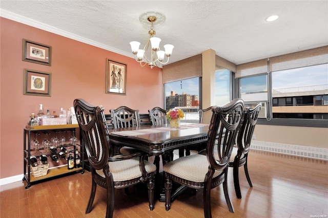 dining space featuring hardwood / wood-style flooring, a notable chandelier, crown molding, and a textured ceiling