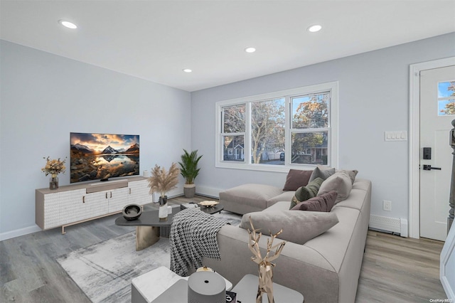 living room with plenty of natural light, a baseboard radiator, and light hardwood / wood-style flooring