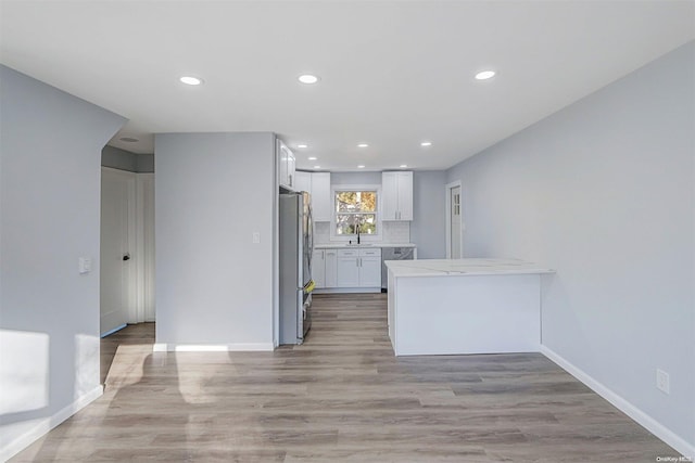 kitchen with sink, light wood-type flooring, white cabinetry, and stainless steel appliances