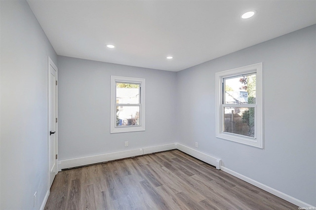 empty room with baseboard heating, light hardwood / wood-style flooring, and plenty of natural light