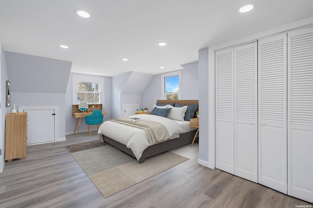 bedroom featuring a closet, light hardwood / wood-style floors, and lofted ceiling