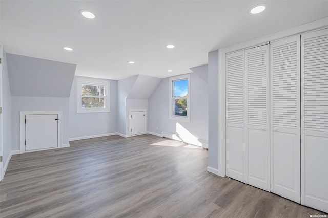 bonus room with vaulted ceiling and light wood-type flooring