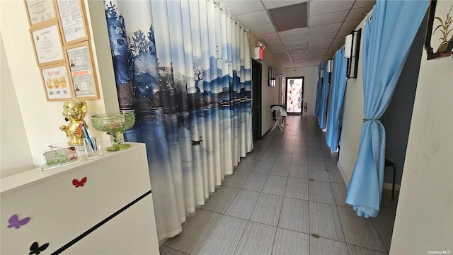 corridor featuring tile patterned floors and a drop ceiling