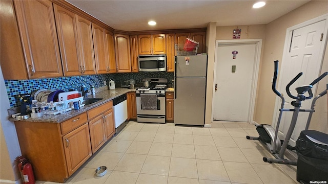 kitchen featuring appliances with stainless steel finishes, tasteful backsplash, light tile patterned floors, and dark stone counters