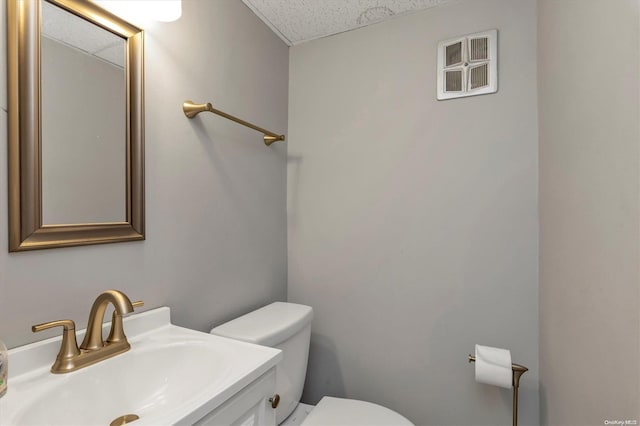 bathroom featuring vanity, toilet, and a textured ceiling