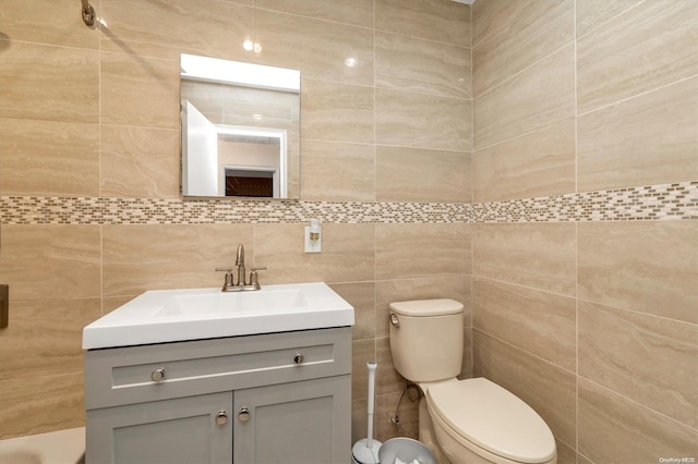 bathroom featuring vanity, tile walls, and toilet