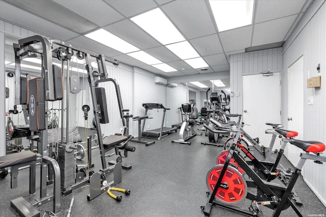 workout area with a wall mounted air conditioner and a drop ceiling