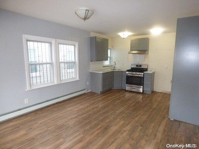 kitchen featuring sink, dark hardwood / wood-style flooring, stainless steel range oven, and baseboard heating