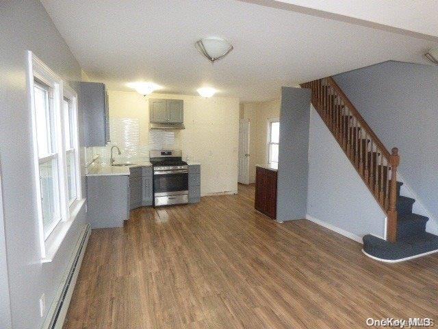 kitchen featuring baseboard heating, dark hardwood / wood-style flooring, a wealth of natural light, and stainless steel range