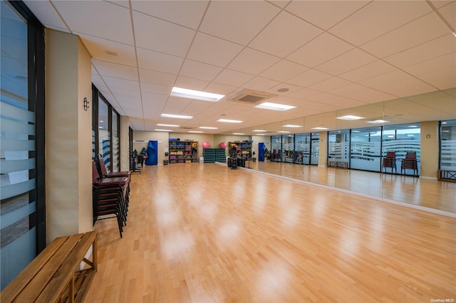 exercise area featuring a drop ceiling and light wood-type flooring