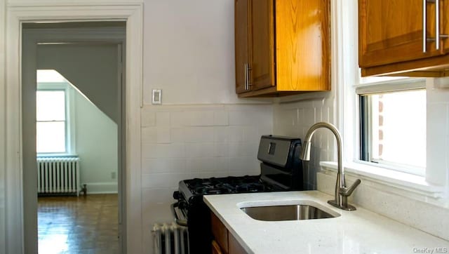 kitchen featuring radiator, gas stove, and sink