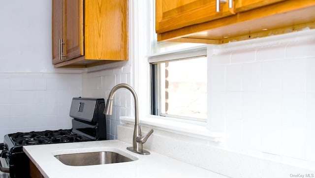 kitchen with sink, black gas stove, and decorative backsplash