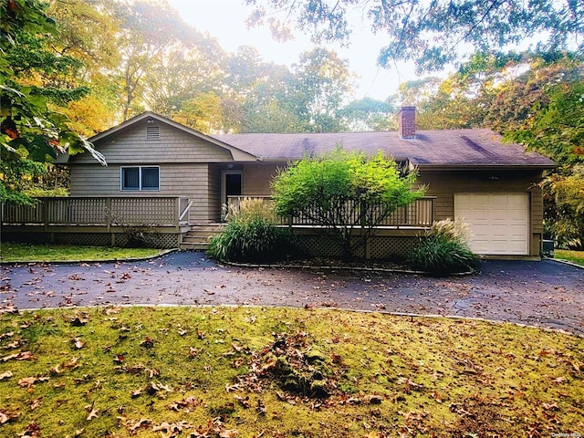 single story home featuring a front yard, a garage, and a wooden deck