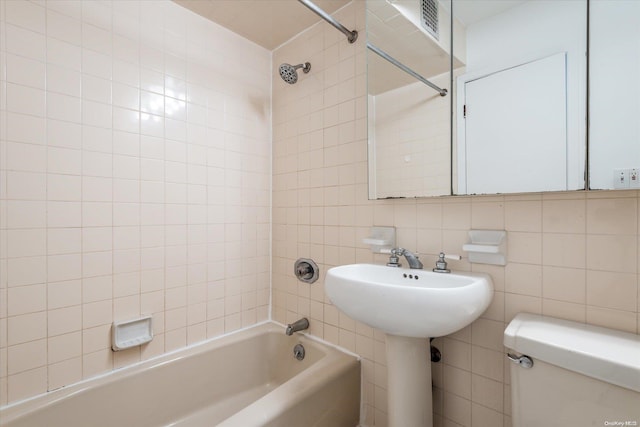 full bathroom featuring tiled shower / bath combo, toilet, tile walls, and backsplash