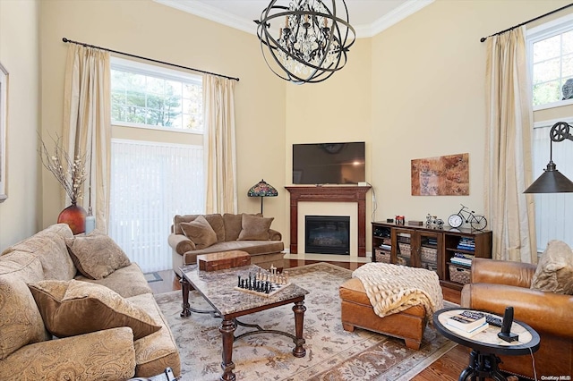 living room featuring a chandelier, ornamental molding, a healthy amount of sunlight, and light wood-type flooring