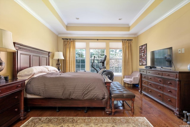 bedroom featuring dark hardwood / wood-style floors, ornamental molding, and a tray ceiling