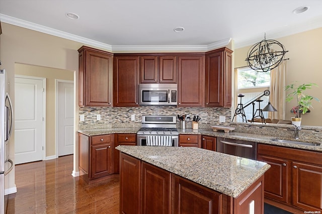 kitchen featuring ornamental molding, stainless steel appliances, dark wood-type flooring, an inviting chandelier, and a center island