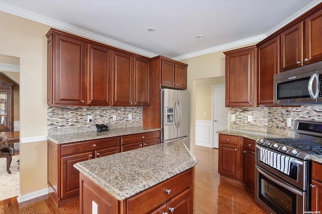 kitchen featuring decorative backsplash, stainless steel appliances, light hardwood / wood-style flooring, and a kitchen island