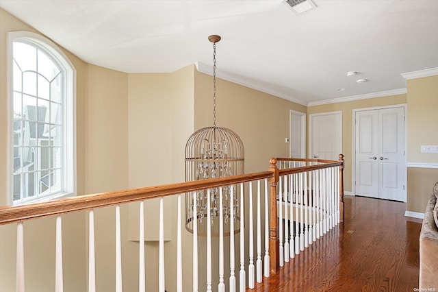 hall featuring an inviting chandelier, dark wood-type flooring, and ornamental molding