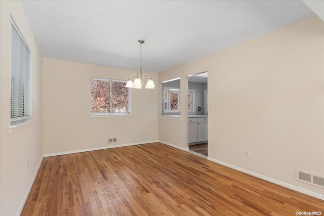 unfurnished dining area with a chandelier and wood-type flooring