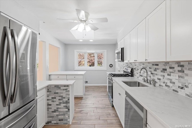 kitchen with white cabinets, sink, light wood-type flooring, appliances with stainless steel finishes, and tasteful backsplash