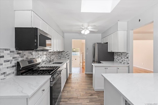 kitchen featuring backsplash, sink, appliances with stainless steel finishes, light hardwood / wood-style floors, and white cabinetry