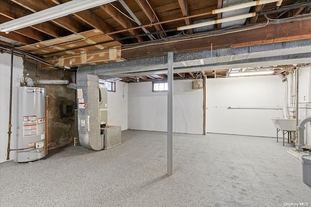 basement featuring heating unit, water heater, and sink