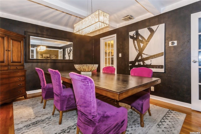 dining room with a chandelier, hardwood / wood-style floors, and beam ceiling