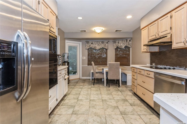 kitchen featuring black appliances, light brown cabinets, and tasteful backsplash