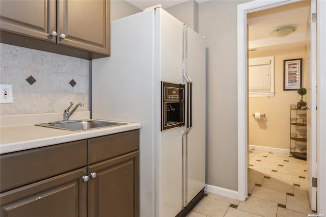 kitchen with dark brown cabinets, light tile patterned floors, sink, and tasteful backsplash