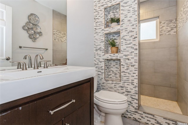 bathroom with a tile shower, vanity, and toilet