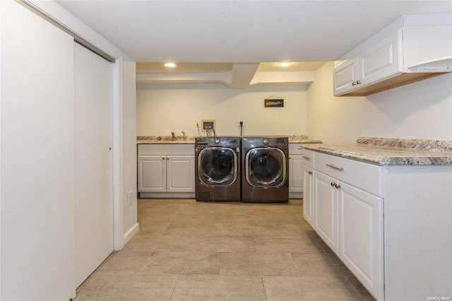 clothes washing area with cabinets, washing machine and dryer, and sink