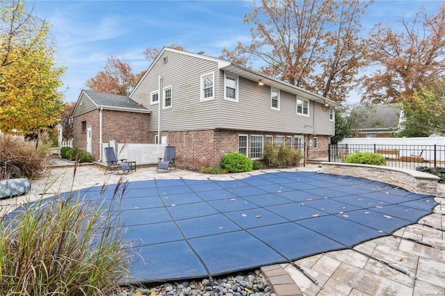 rear view of house featuring a covered pool and a patio area