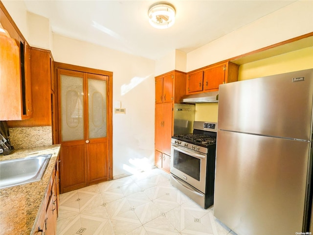 kitchen with light stone counters, sink, and appliances with stainless steel finishes