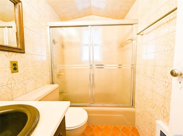 full bathroom featuring vanity, toilet, combined bath / shower with glass door, and tile walls