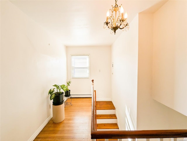 staircase with a chandelier, wood-type flooring, and baseboard heating