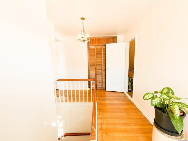 hall with hardwood / wood-style floors and a chandelier