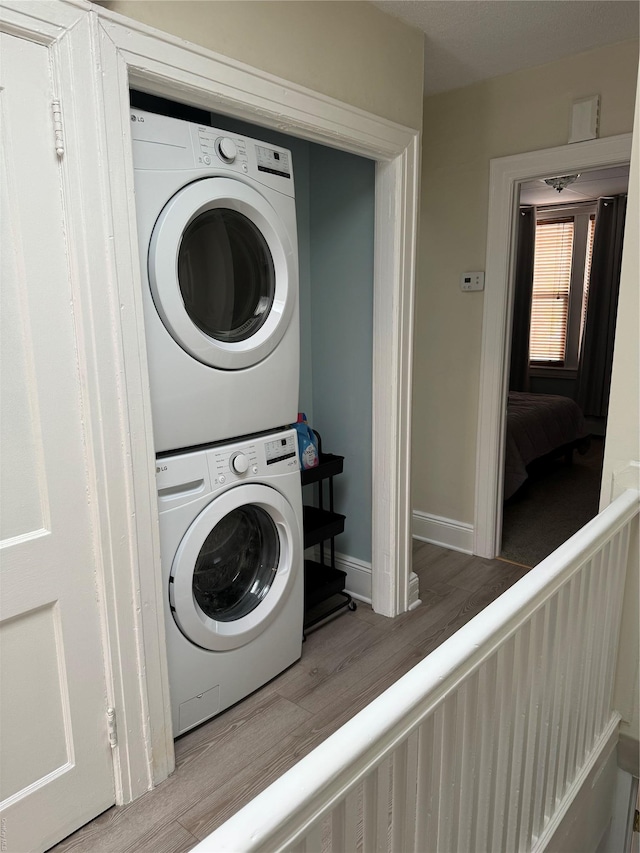 147 E 29th St, Brooklyn, NY 11226 - clothes washing area featuring stacked washer / dryer, wood finished floors, and baseboards