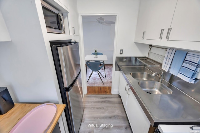 kitchen featuring white cabinets, appliances with stainless steel finishes, light wood-type flooring, and sink