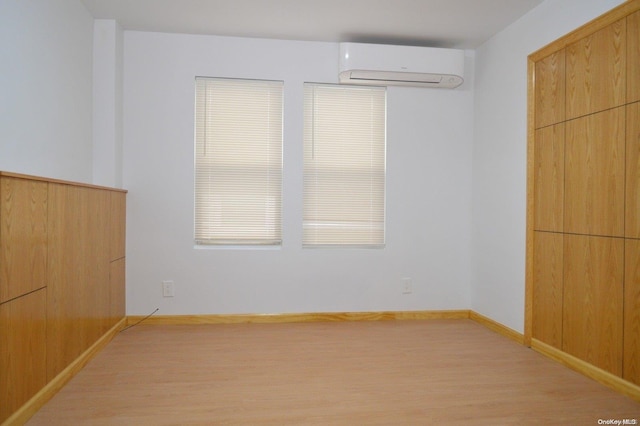 unfurnished bedroom featuring light hardwood / wood-style floors and a wall mounted AC